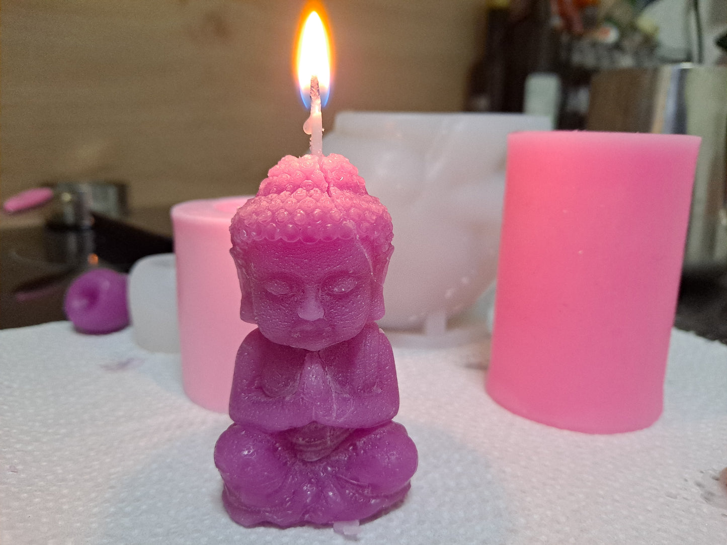 Vela de cera de abeja con forma de Buda, recién sacada del molde y encendida