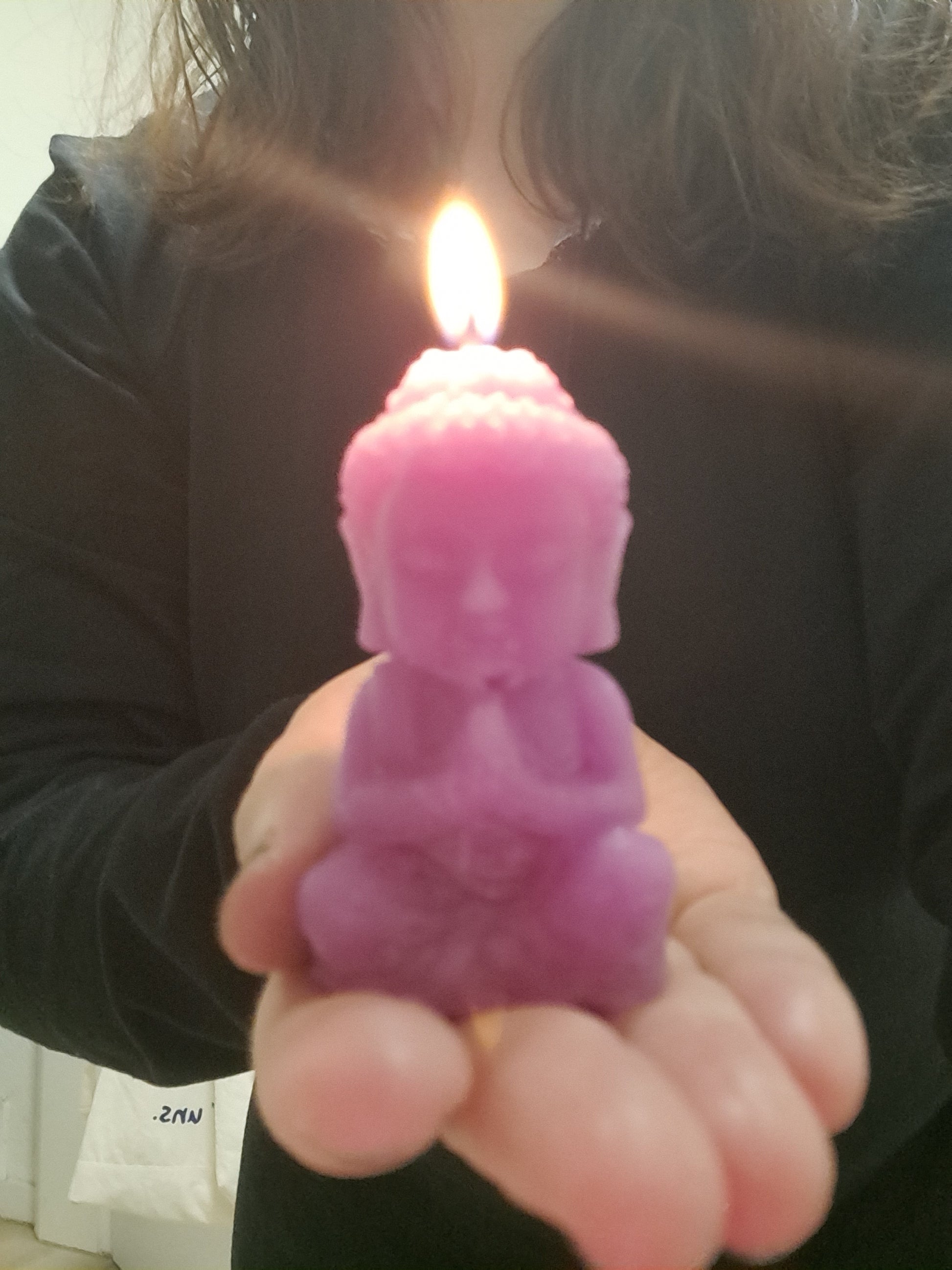 Vela de cera de abeja con forma de Buda, encendida en mi mano