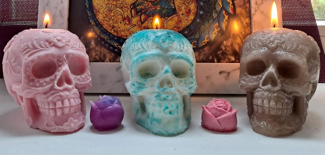 Velas de colores variados con forma de calavera encendidas